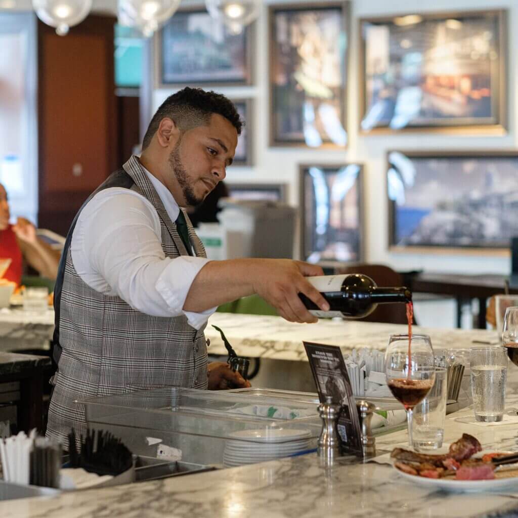 S&W waiter is pouring red wine into a glass